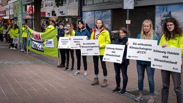 Menschen in einer Reihe halten Schilder für den Klimaschutz